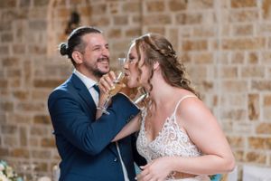 Intimate moment during wedding dance in rustic stone wall venue.