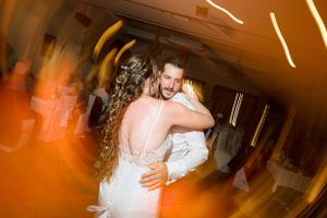 Dancing couple embracing in warm orange lighting at reception venue.