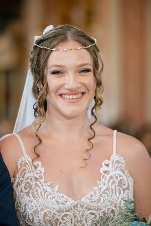 Bride wearing delicate tiara and lace dress with natural curled hairstyle.
