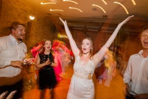 Energetic dancing and celebration at wedding reception with orange ambient lighting.