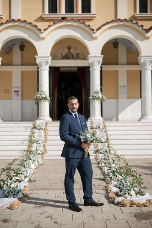 Wedding scene at ornate building entrance with floral decorations and classical architecture.
