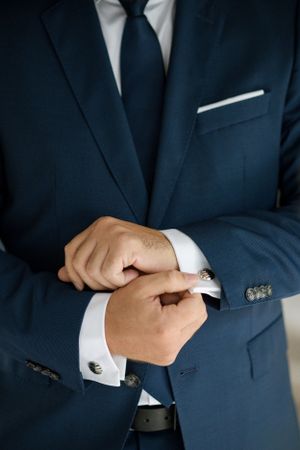Close-up of navy suit showing detailed cufflinks and pocket square styling.