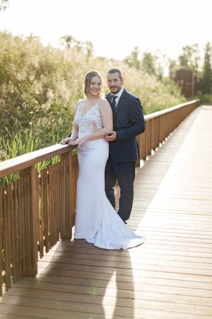 Elegant wedding photoshoot on a wooden boardwalk amidst natural scenery.