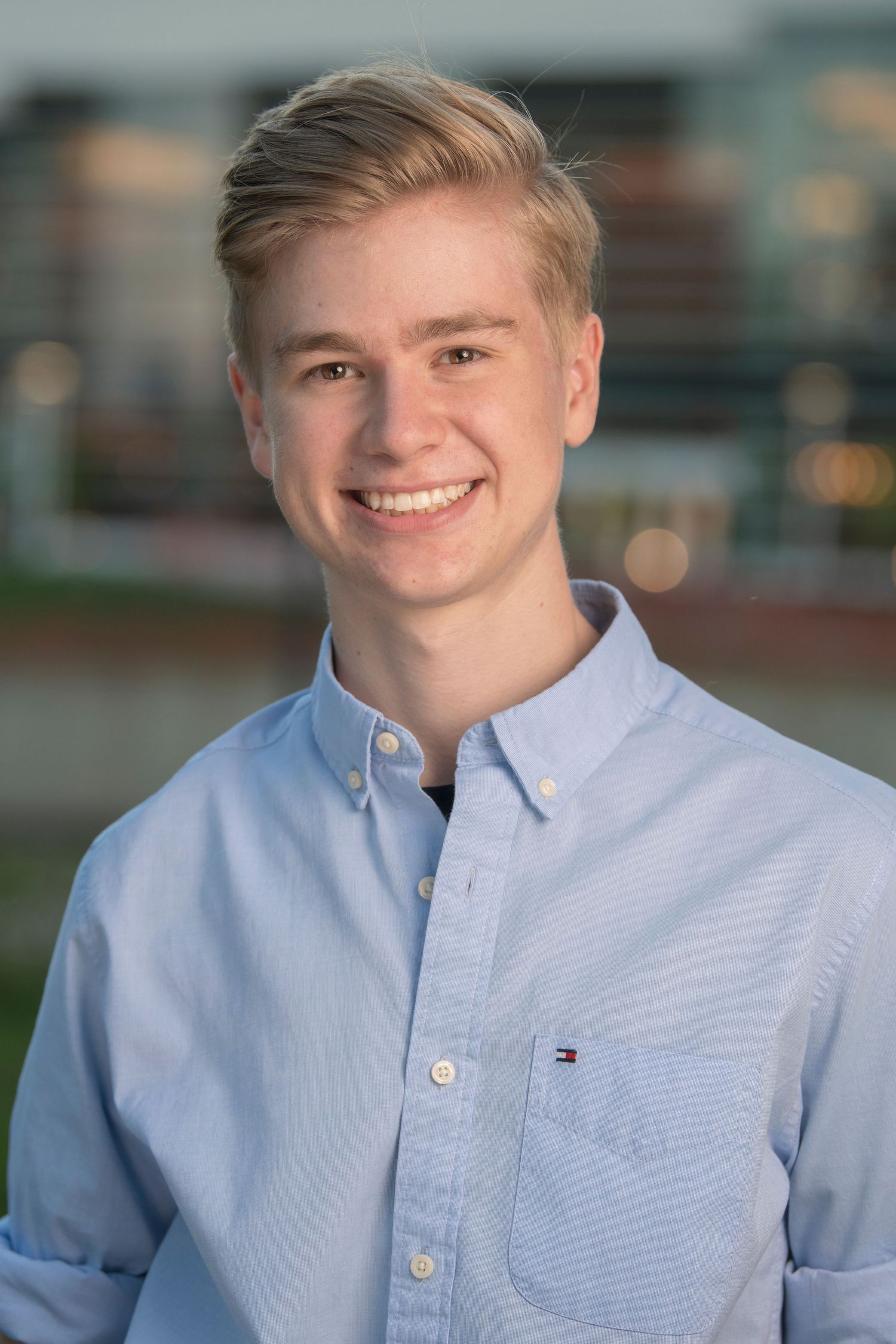 Professional headshot against blurred background with warm lighting.