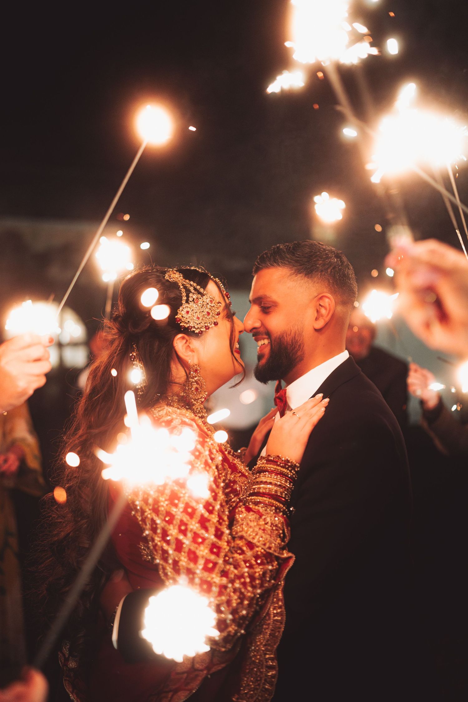 A romantic moment captured during a sparkler celebration at an evening wedding celebration.