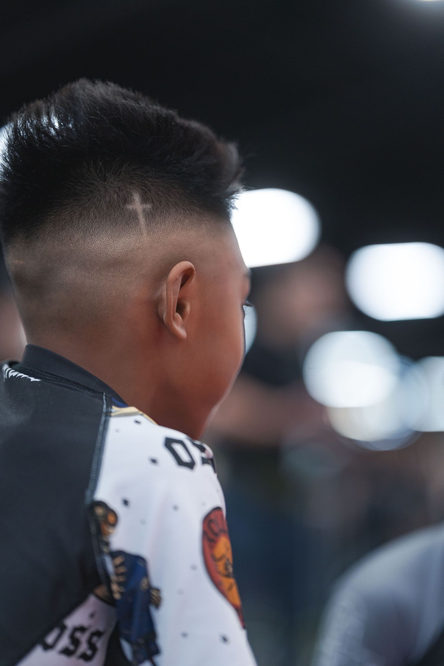 Close-up side profile of a spectator with a fresh fade haircut watching a sports event.