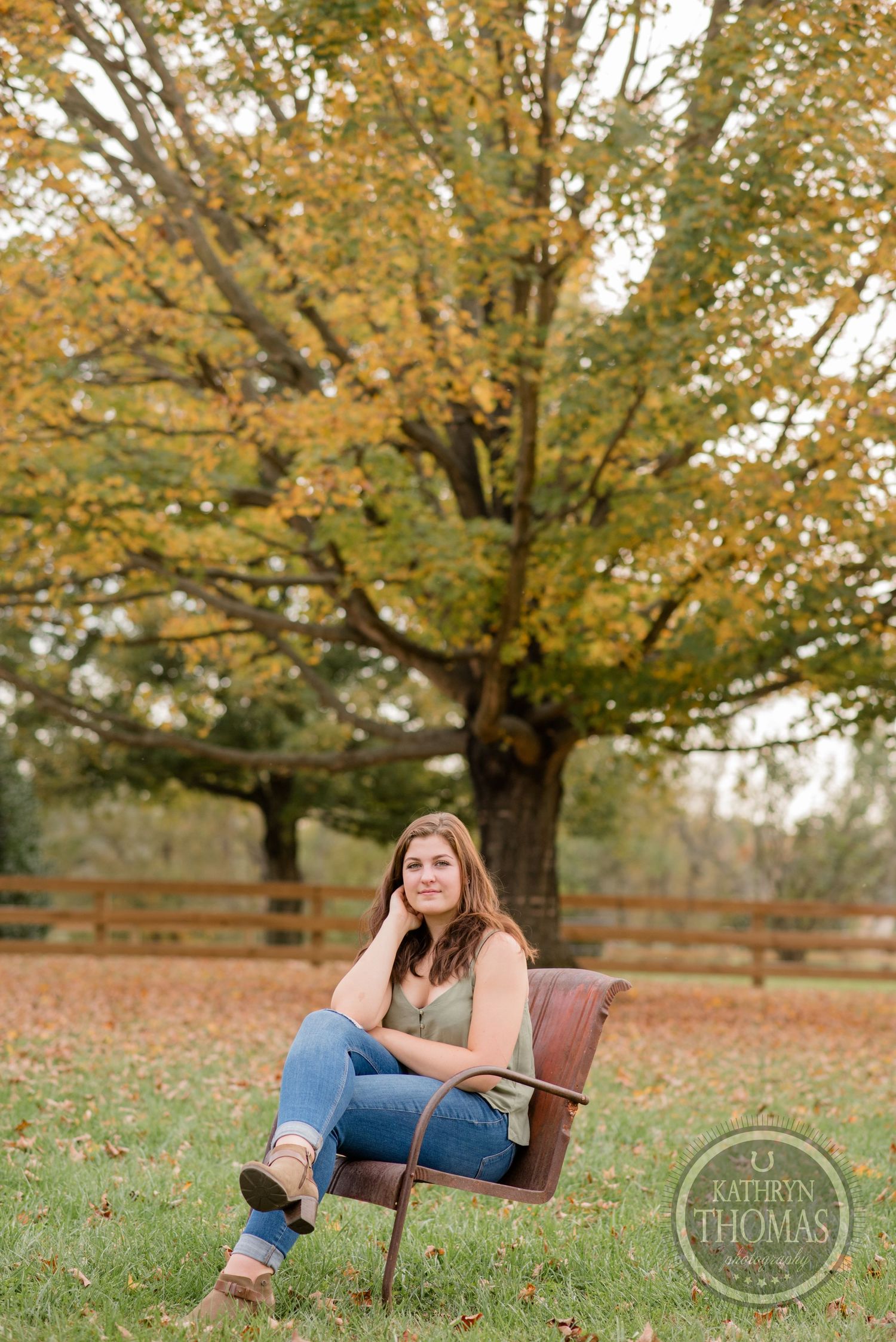 Person sits in vintage chair surrounded by autumn leaves and golden trees.