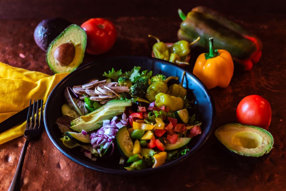 Colorful Mexican-style bowl with avocado, peppers, and fresh vegetables on rustic background for restaurant branding photography.