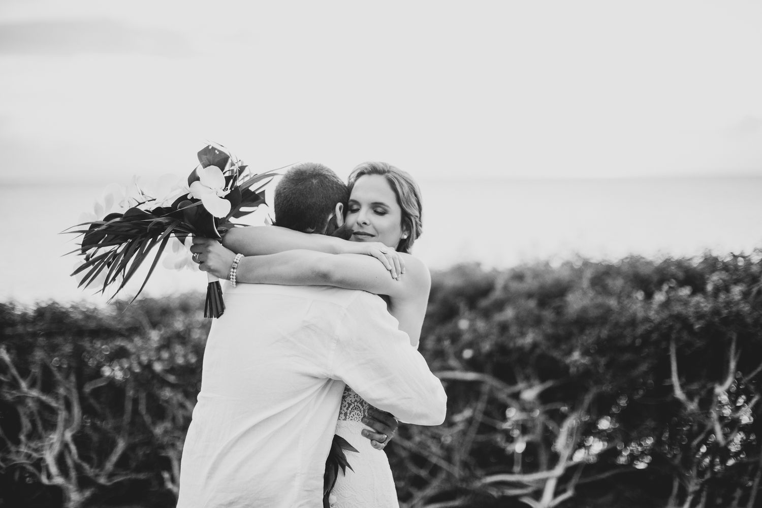 Black and white photo of tender moment during outdoor wedding ceremony.