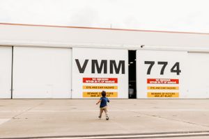 Child running past white hangar with VMM 774 signage.