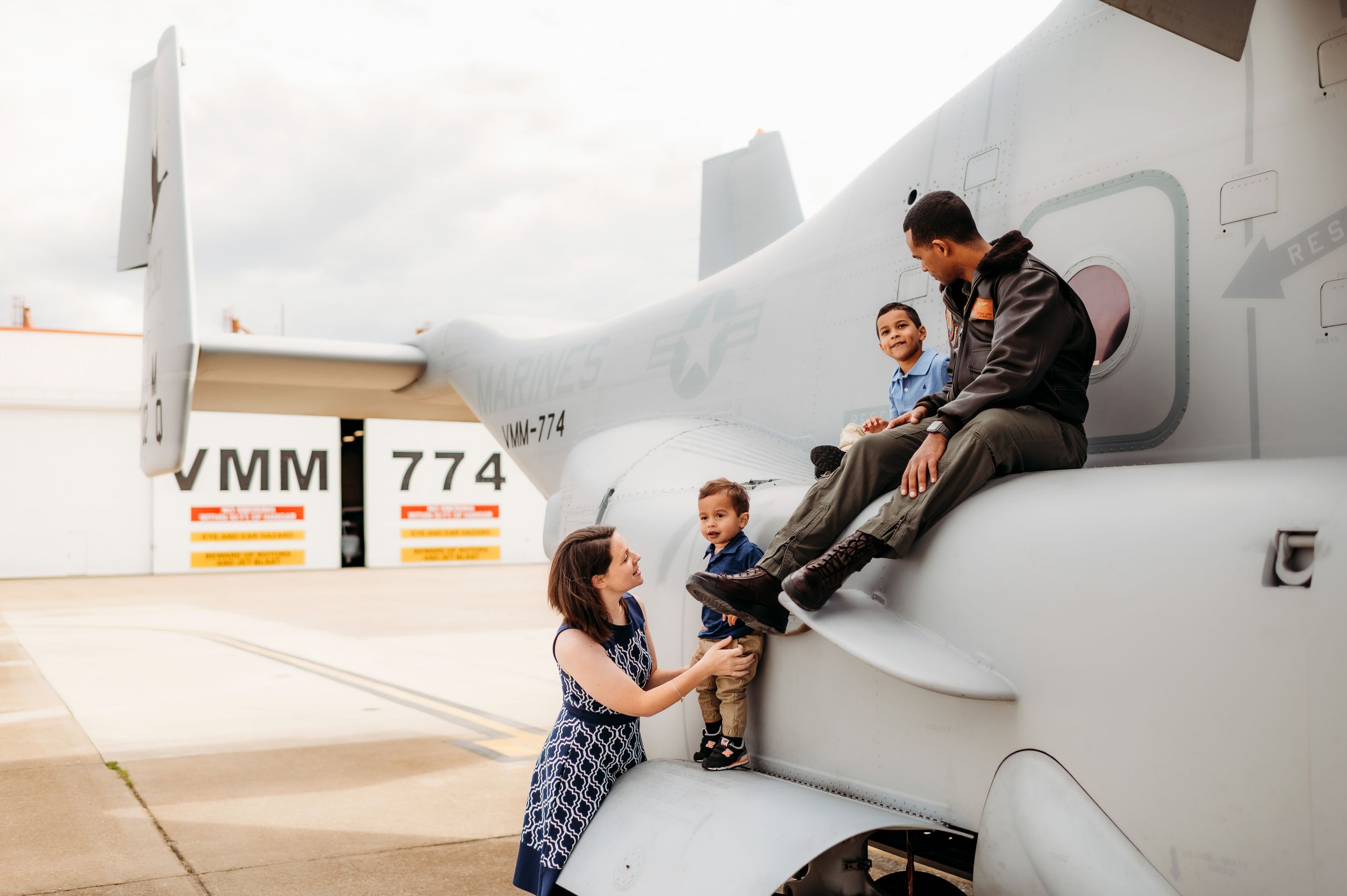 Family sharing a special moment together on a military aircraft wing during a base visit.