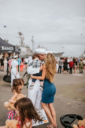 Military homecoming scene with families reuniting on a naval base.