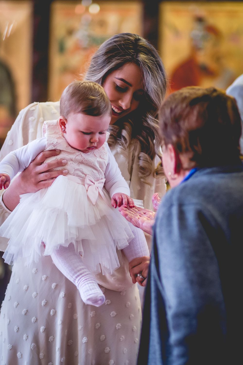 Tender moment during baptism ceremony with baby wearing white dress.