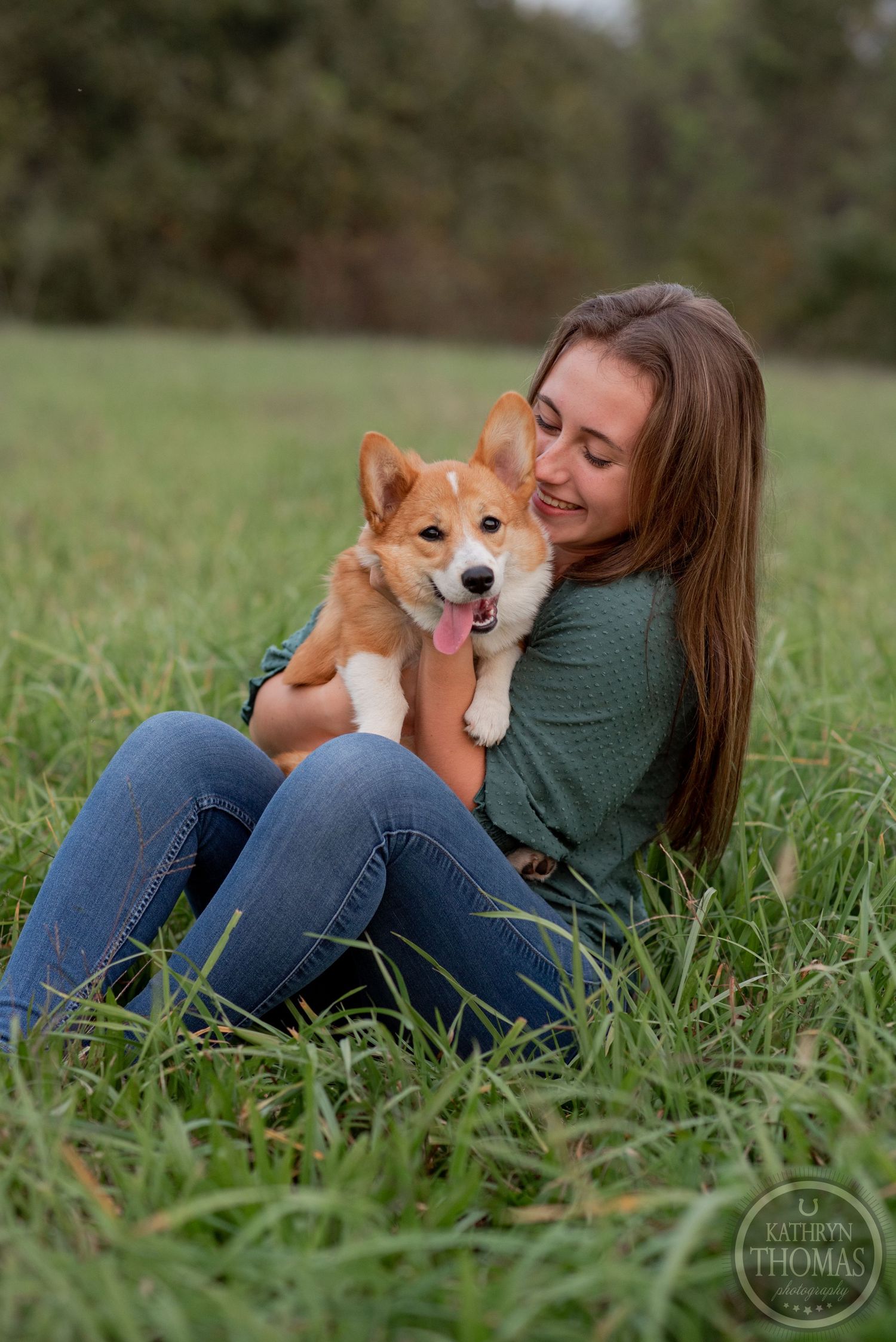 Joyful moment between a Corgi puppy and its owner sitting in tall grass outdoors.