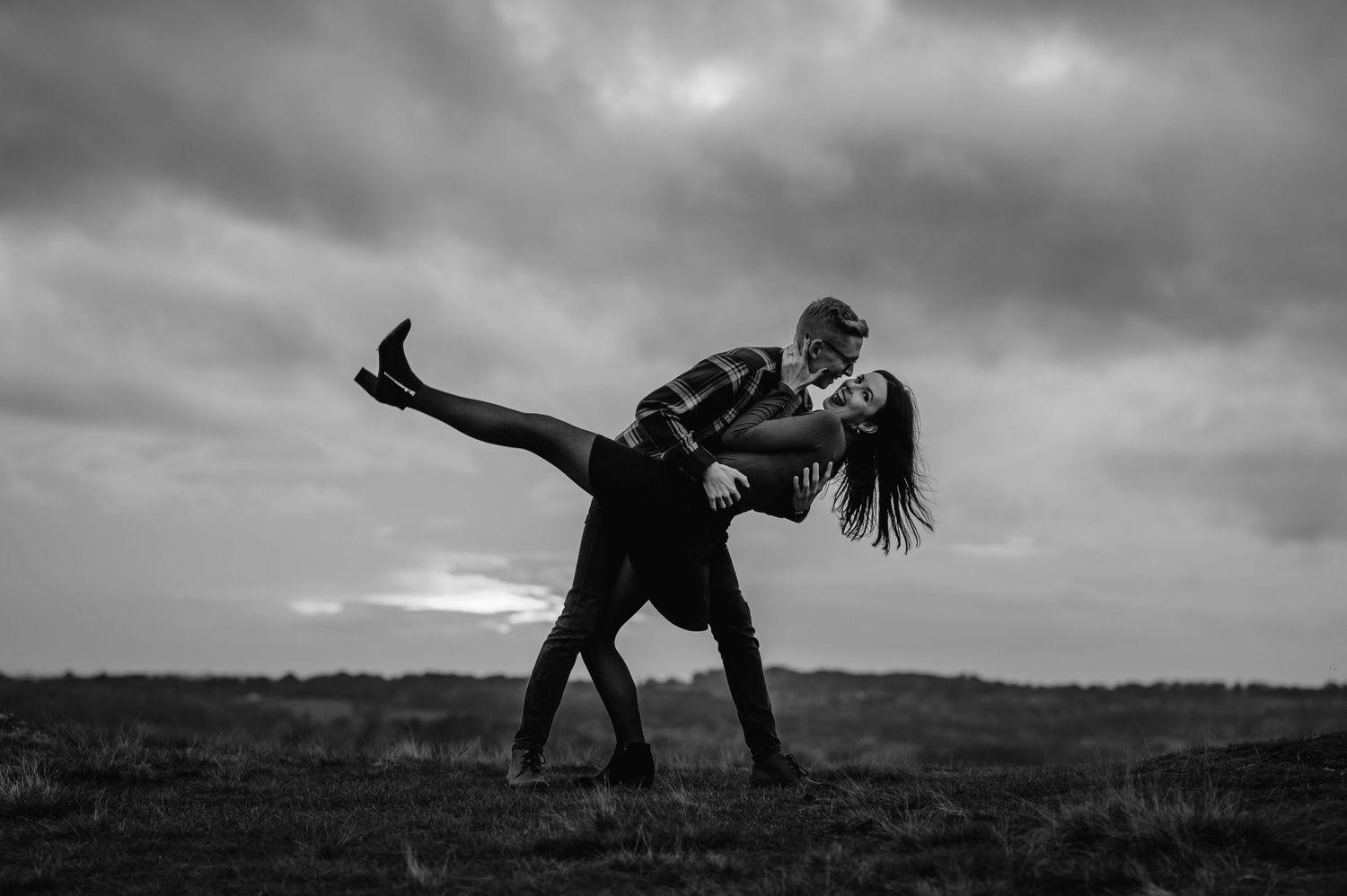 A dramatic black and white dance pose against a moody sky.