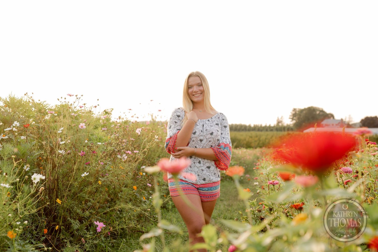 Walking through a blooming wildflower garden in a floral print dress during golden hour.