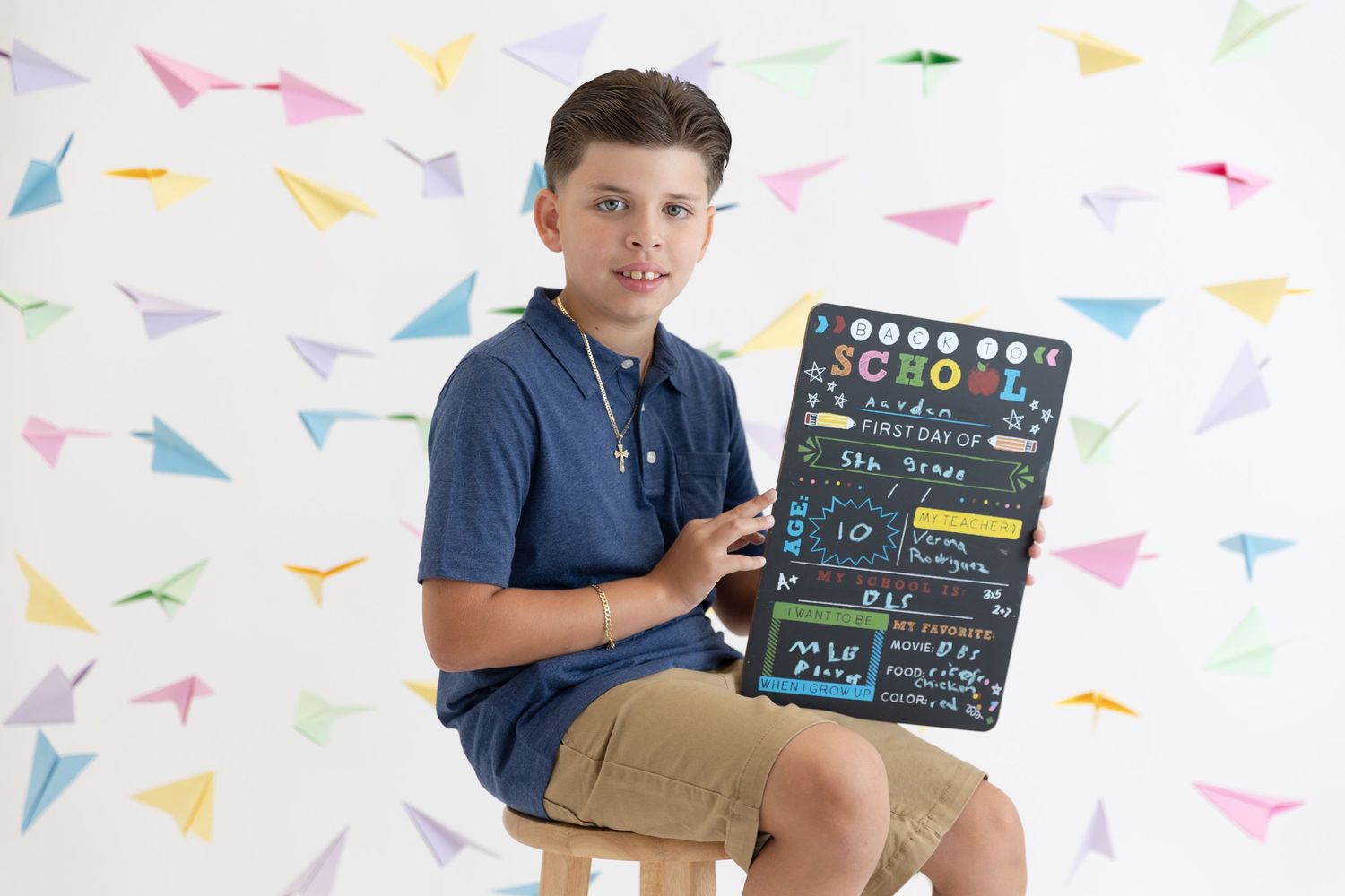 Creative back-to-school portrait with colorful paper airplanes and chalkboard sign.