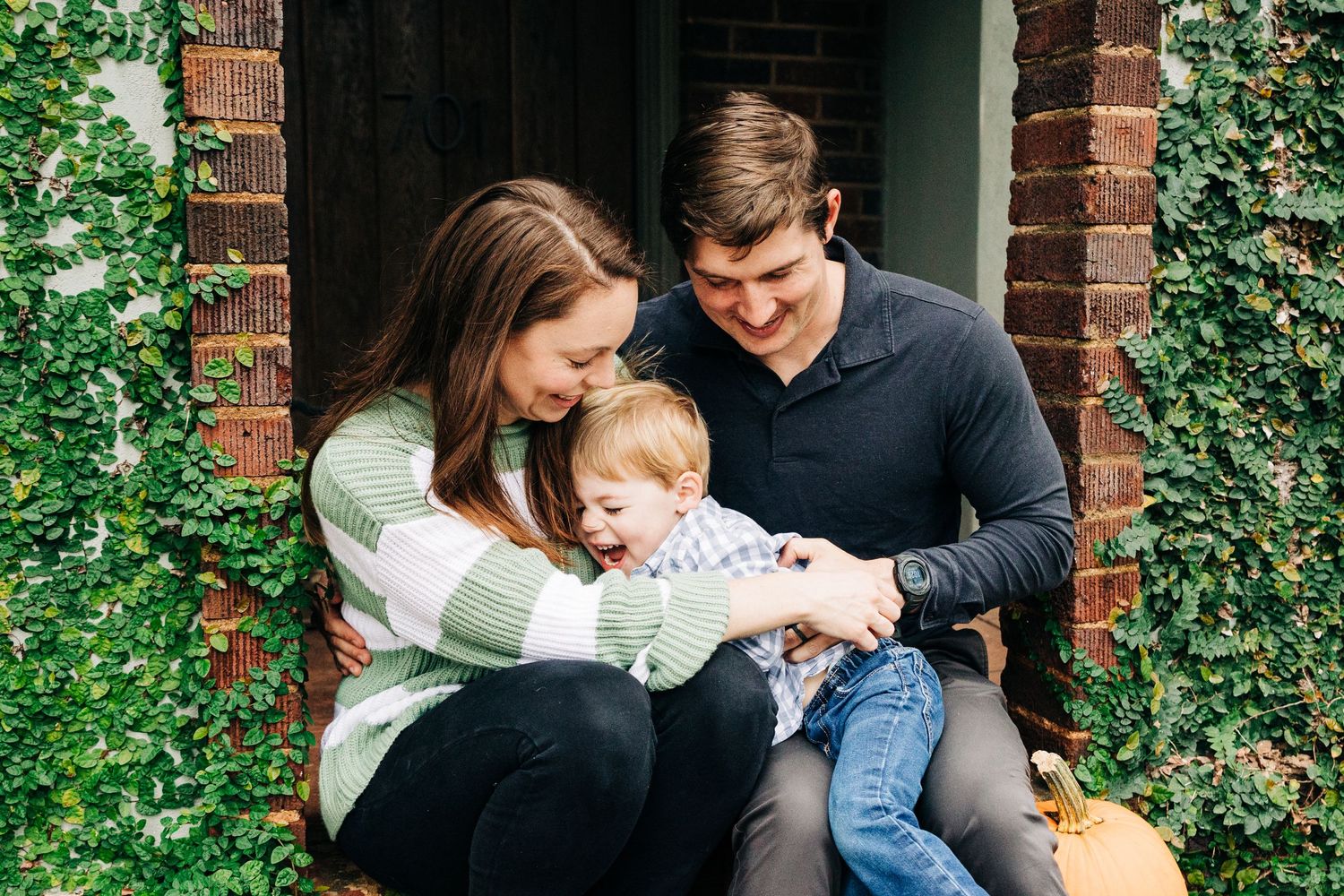 Family of 3 snuggling on their porch and tickling and smiling