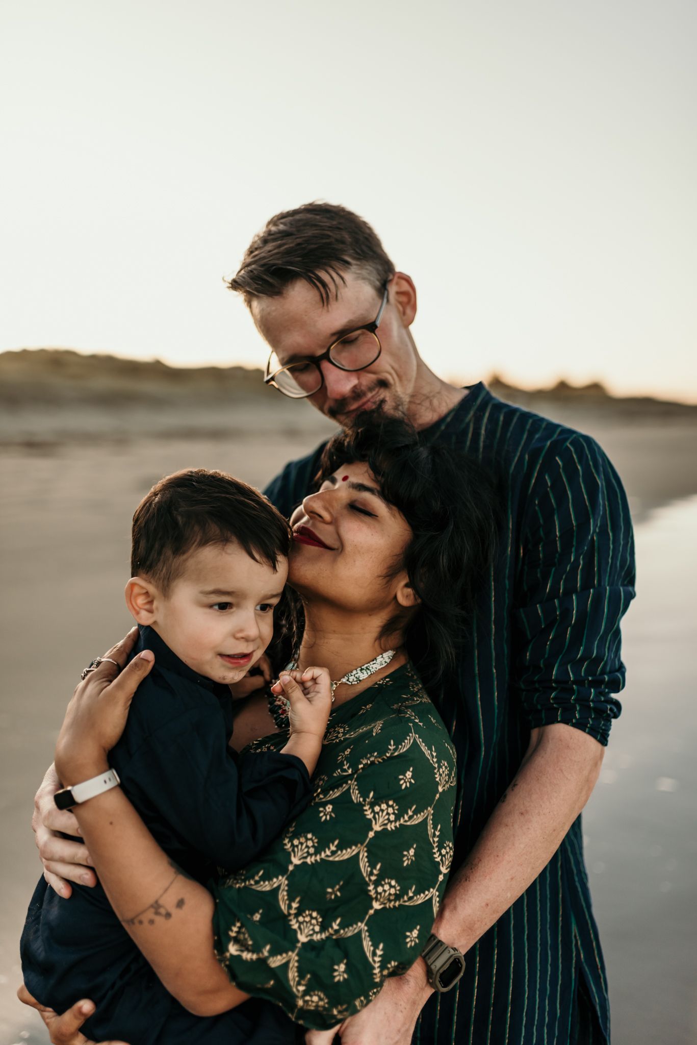 An intimate family moment captured on the beach during golden hour.