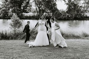 Wedding party members posing on grassy lawn near trees in black and white photograph.