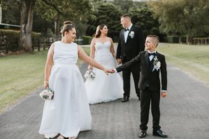Wedding party walking together on paved path outdoors.