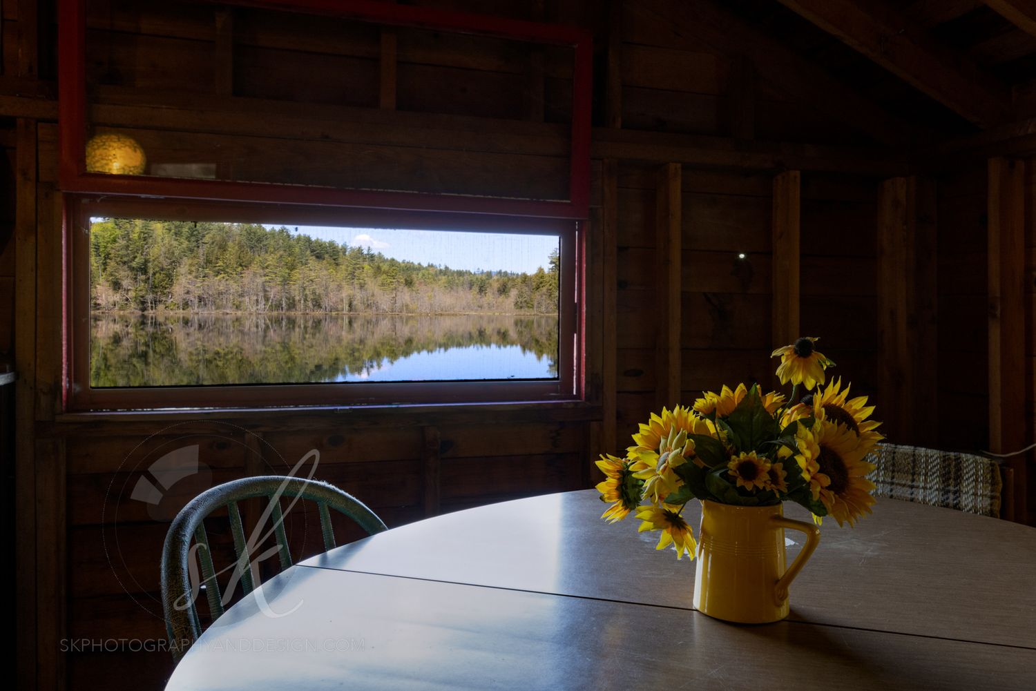 Professional real estate photo from inside an Adirondack boathouse with a window looking out to a scenic reflection on friends lake.