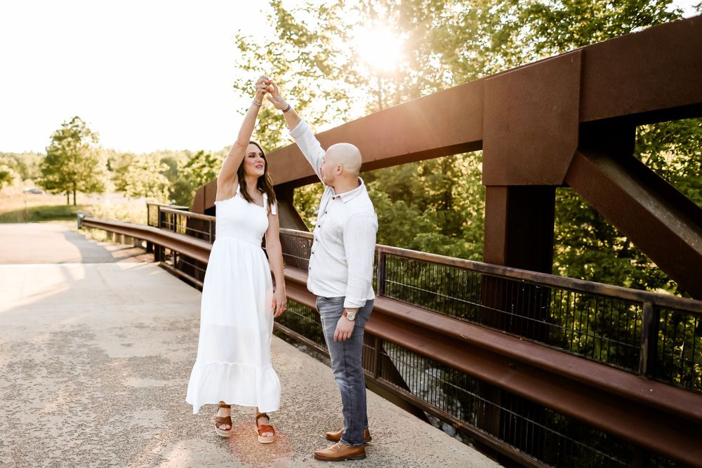 Couple dancing together on a rustic bridge during golden hour.