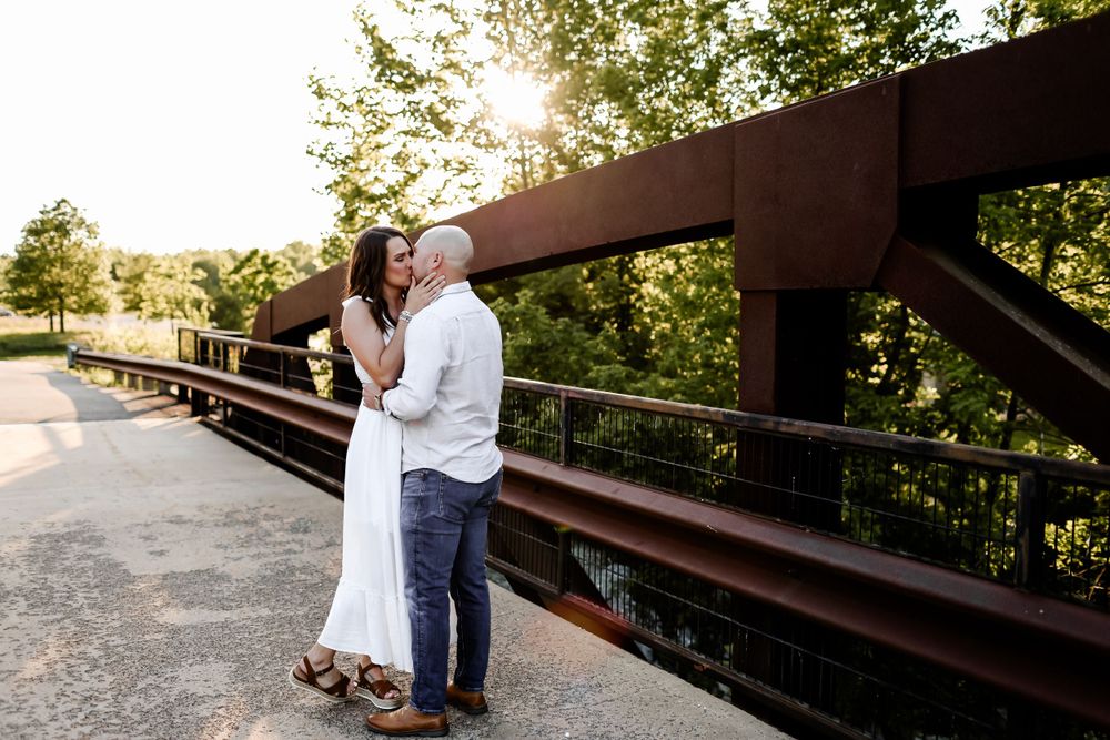 Couple embracing on a metal bridge during sunset.