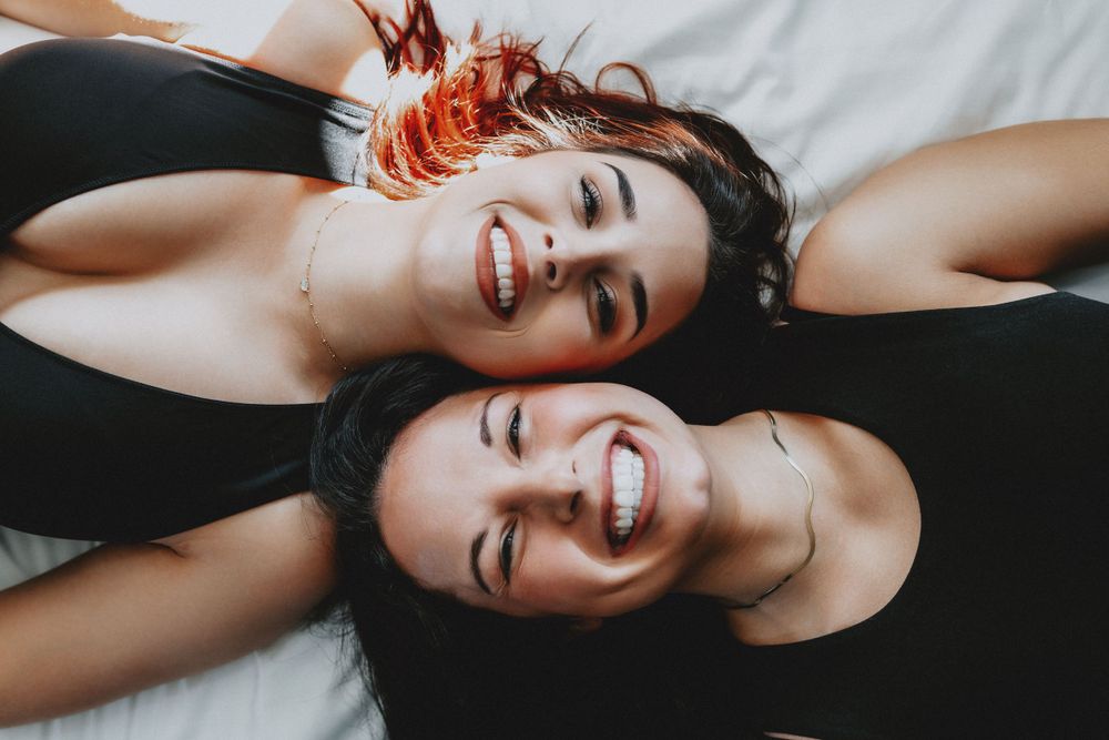 Best friends lying head to head on white surface, one with black hair and one with red hair in Cincinnati