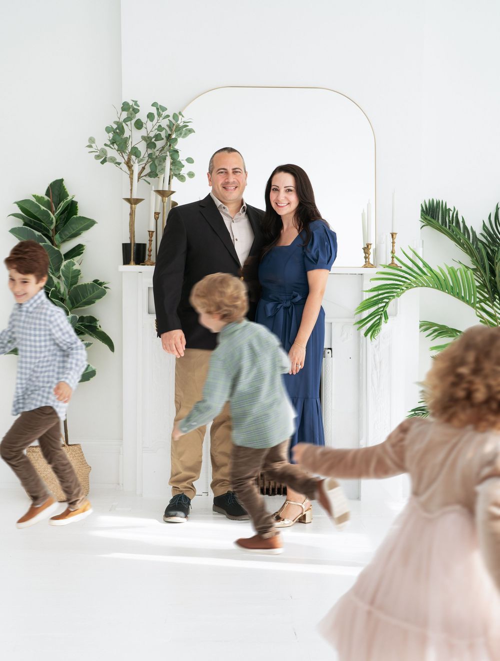 Young couple posing while their children run around a Cincinnati photo studio