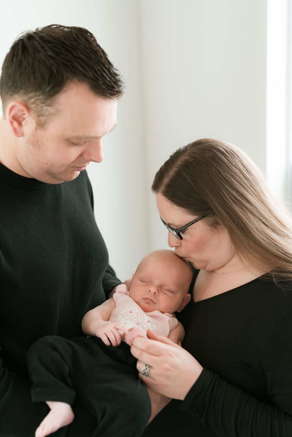 Couple with baby. Mother kissing baby on the head while father watches