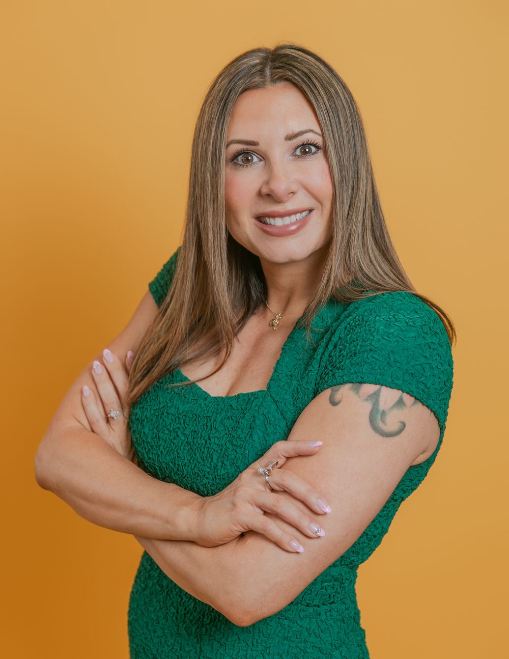 Woman in emerald green sweater shows different poses against orange background with a warm friendly expression.