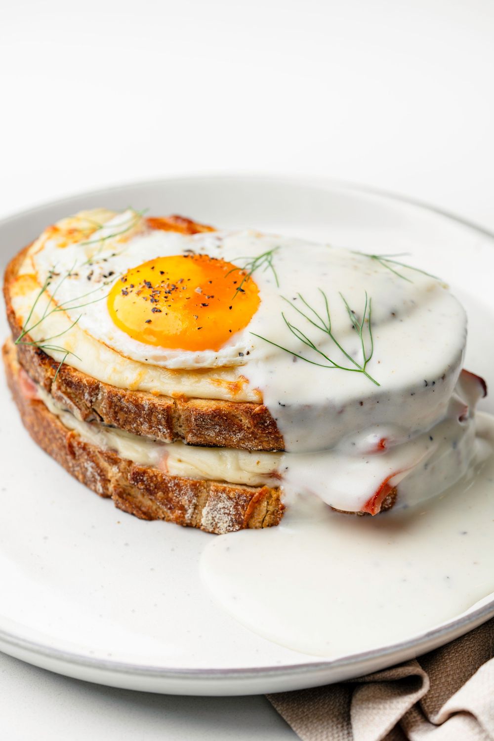 Sunny side up egg on toast with fresh dill garnish on white plate.