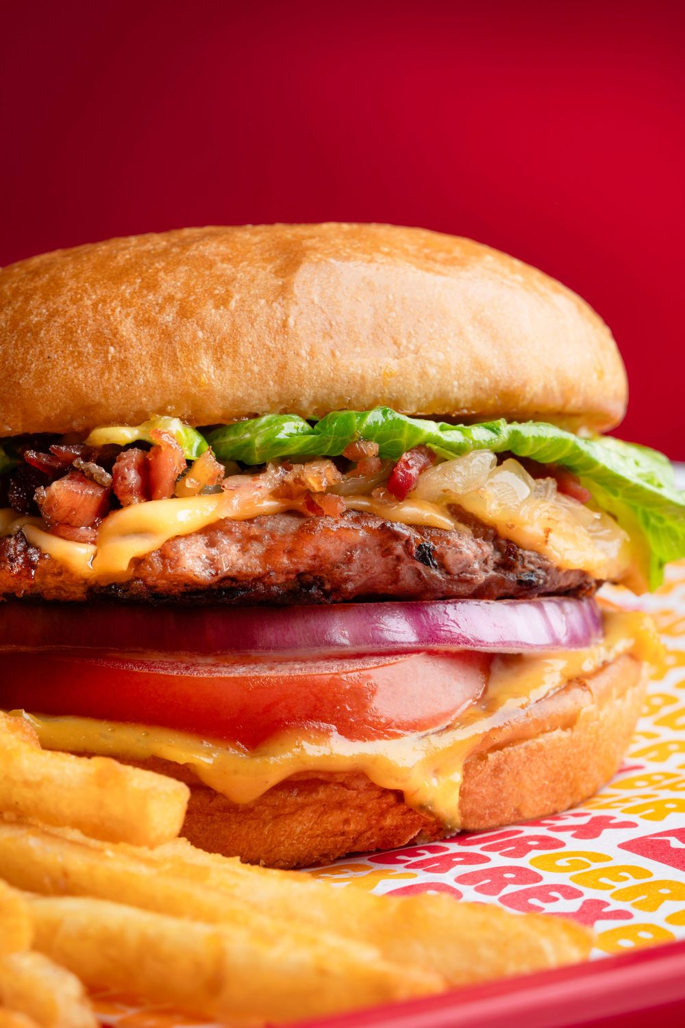Close-up of cheeseburger with melted cheese and toppings on red serving tray.