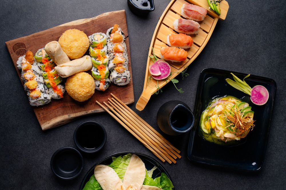 Japanese cuisine presentation featuring sushi rolls and appetizers on dark wooden boards.