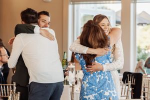 Wedding guests sharing warm embraces during an indoor reception.