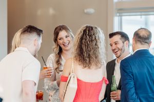 Friends gathered in a well-lit room sharing drinks and laughter at a social gathering.