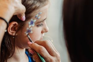 Close-up of face painting with delicate blue floral designs being applied.