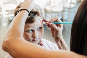 Face painting in progress as an artist applies designs to a young guest.