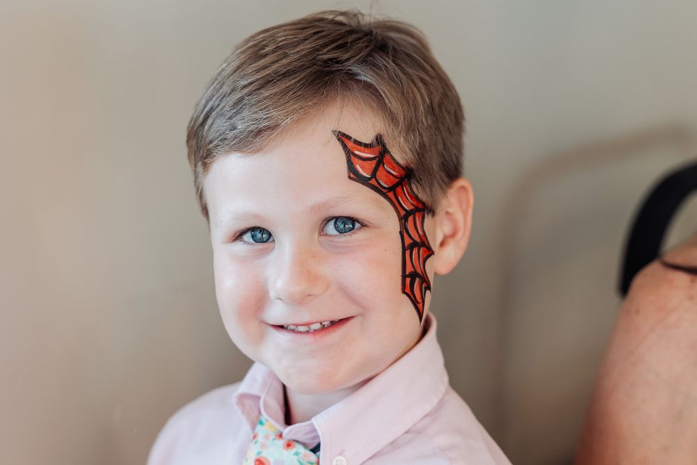 A young party guest with a red and black spider web design face paint.