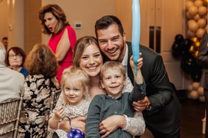 Family celebration with light-up balloon swords and festive decorations in the background.