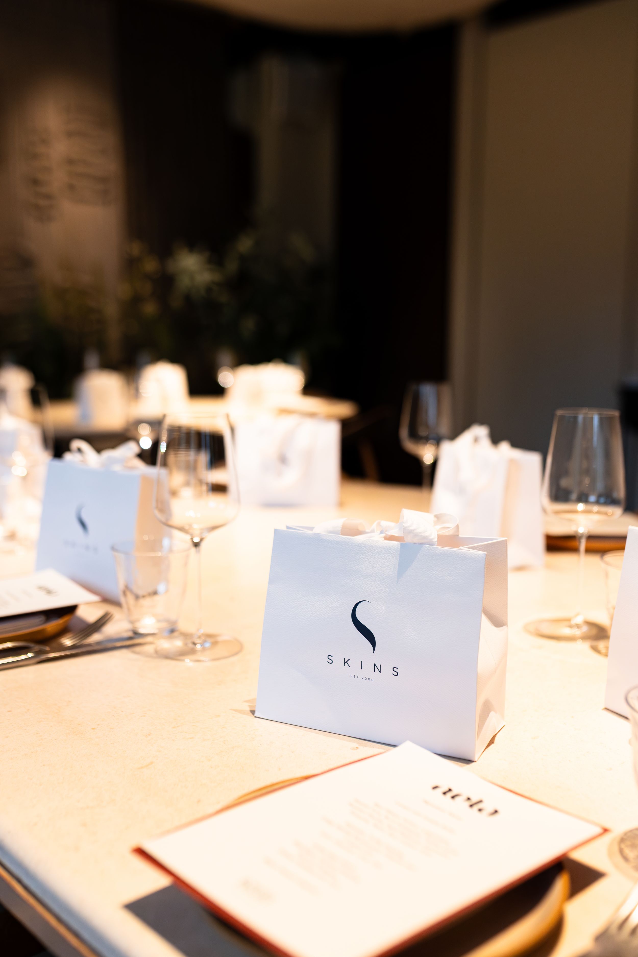 Minimalist white table settings with branded place cards in soft lighting.