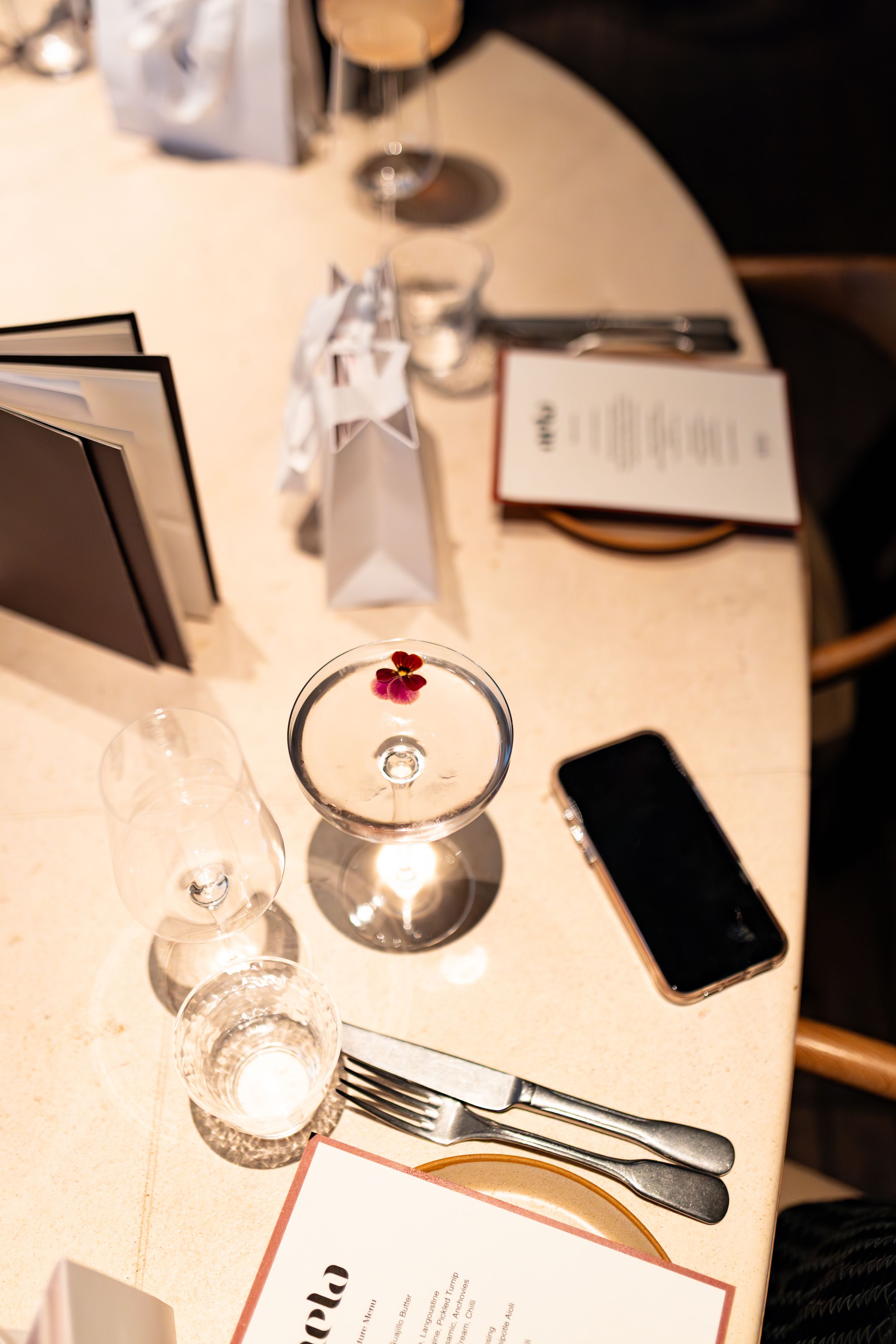 Elegant table setting with wine glasses and silverware in warm lighting.