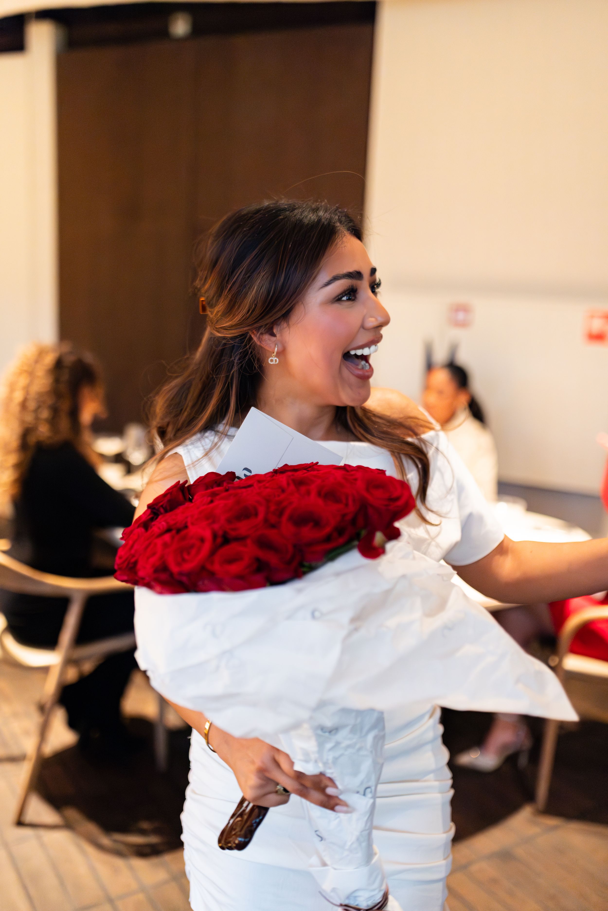 Elegant dining event with decorative red roses and white attire.