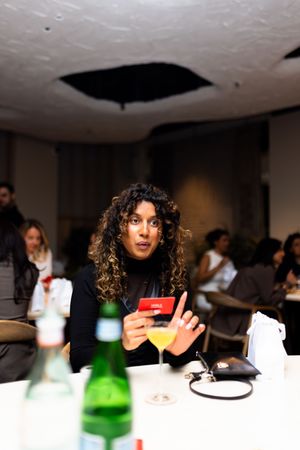 Group enjoying drinks and conversation at a dimly lit dinner gathering.