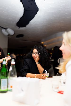 Friends socializing around a dinner table with drinks and conversation.