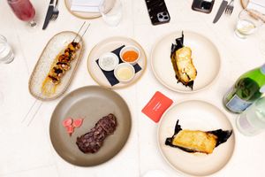 Overhead view of elegant plated dishes and drinks on a white tablecloth.
