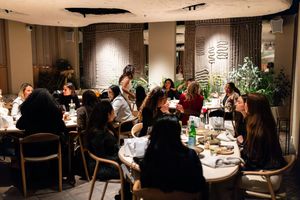 Wide view of a restaurant dining room with multiple tables of guests enjoying dinner.