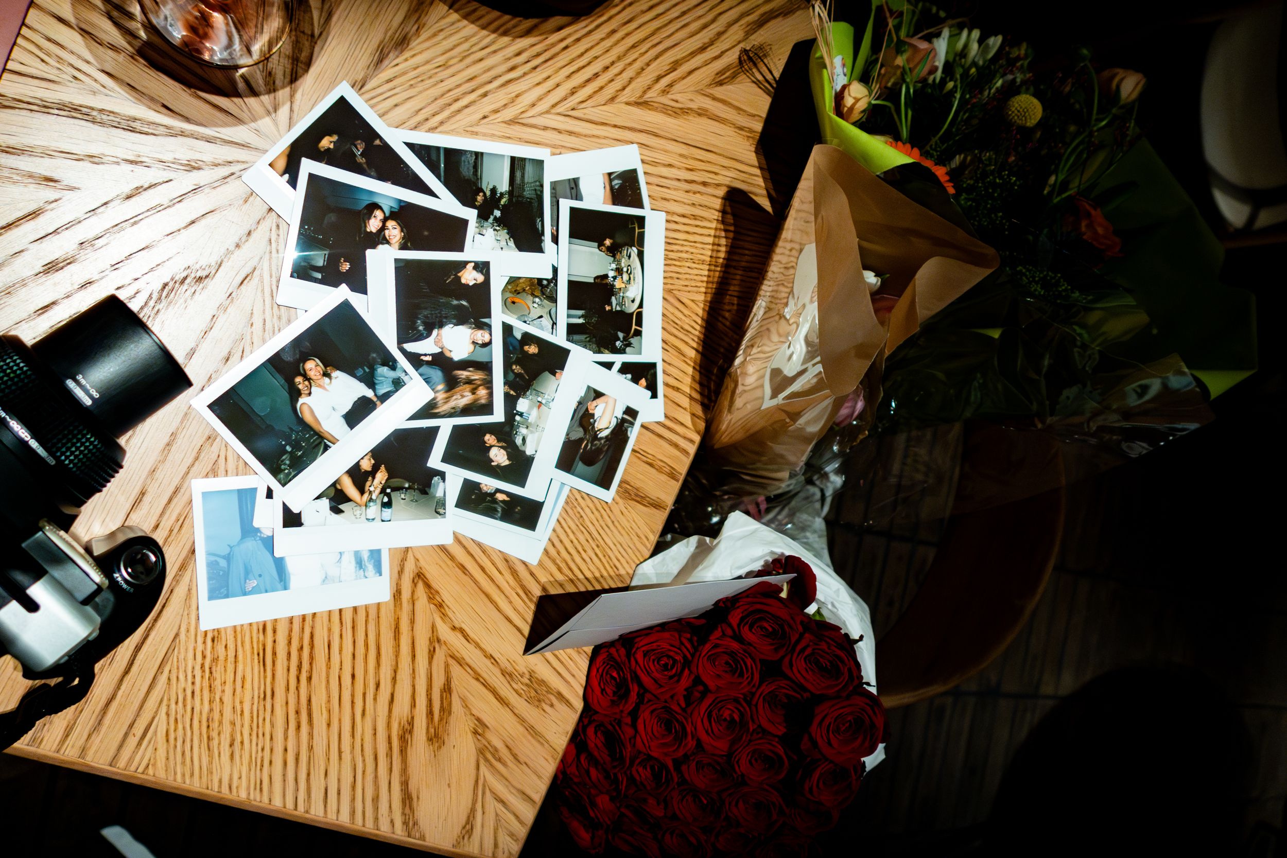 Collection of vintage photographs scattered on a wooden table surface.