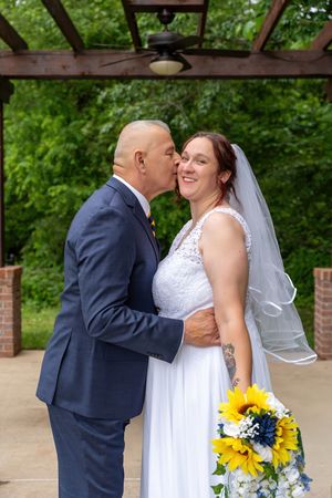 A newly married man kisses his bride on the cheek